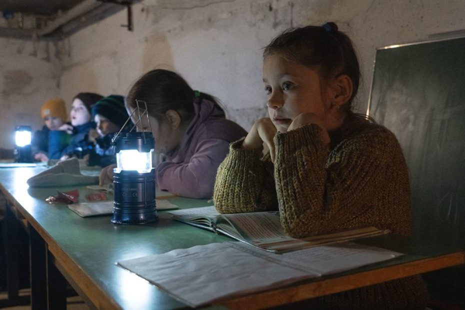 © UNICEF/Aleksey Filippov Children in Borodianka, Ukraine, study under lamplight in a shelter.