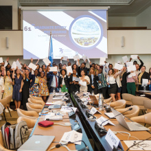 A group of young persons cheering in a conference room, certificates in their hands