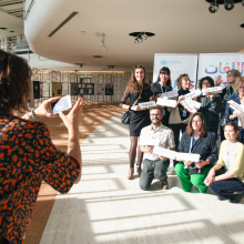 A person taking a photo with a mobile phone of a group showing their language abilities on different cards.