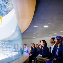 A visiting group sitting in the gallery of the Human Rights Council Room and marveling at the room's colorful ceiling.
