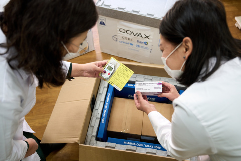 2 health care workers pack COVID-19 vaccines. 