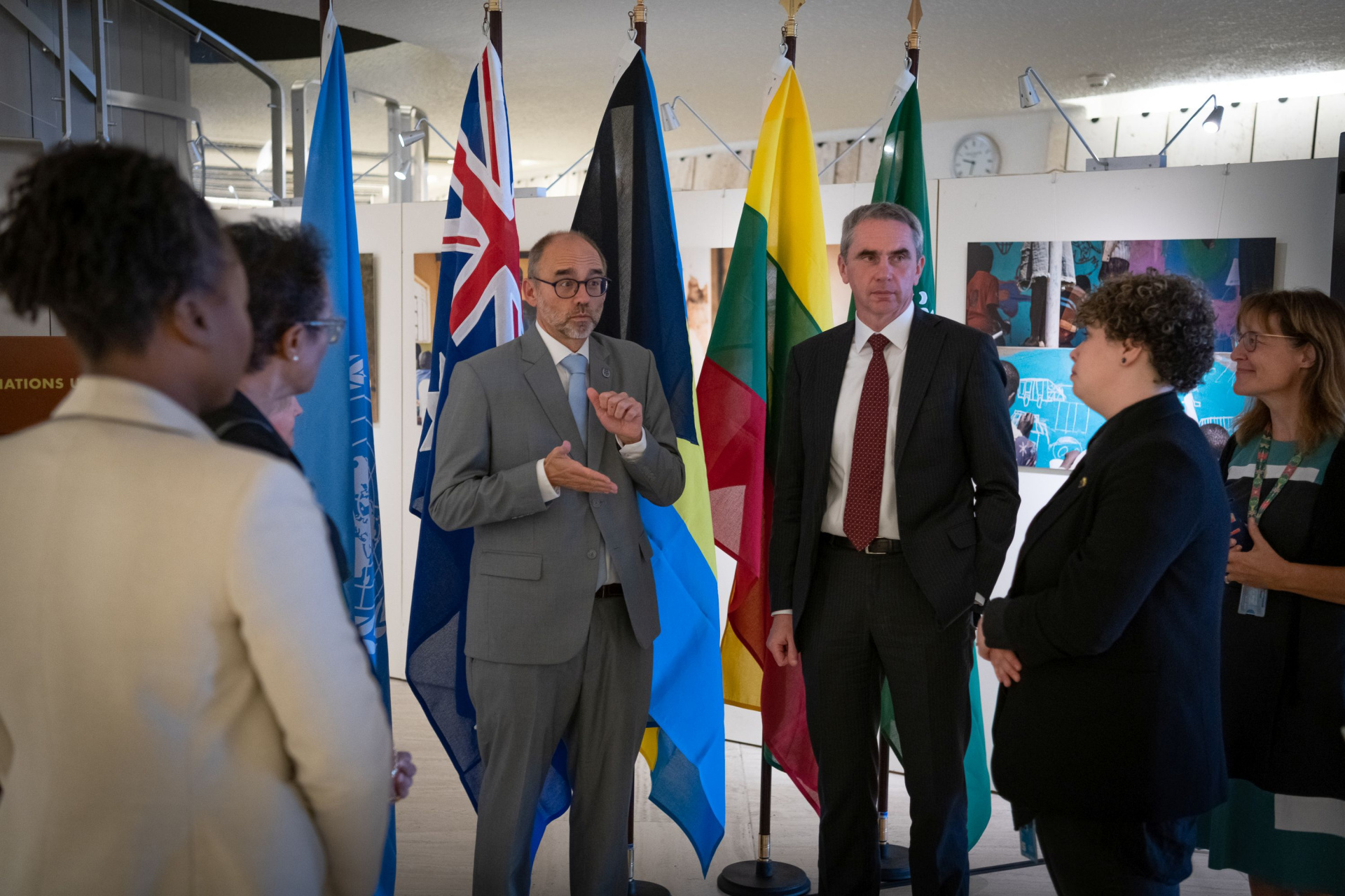 A group of people communicating in front of country flags, some of them in sign