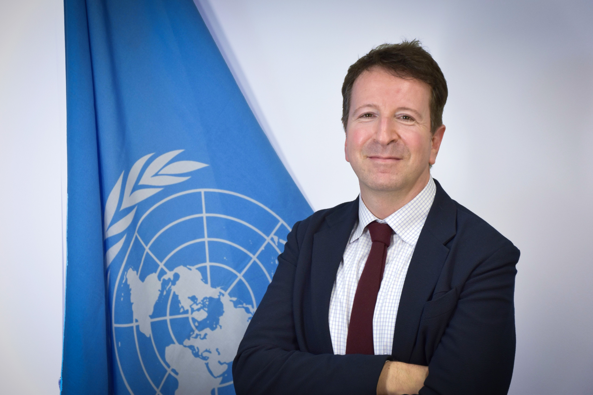 A portrait photo of Stephen Slawsky in front of the UN flag