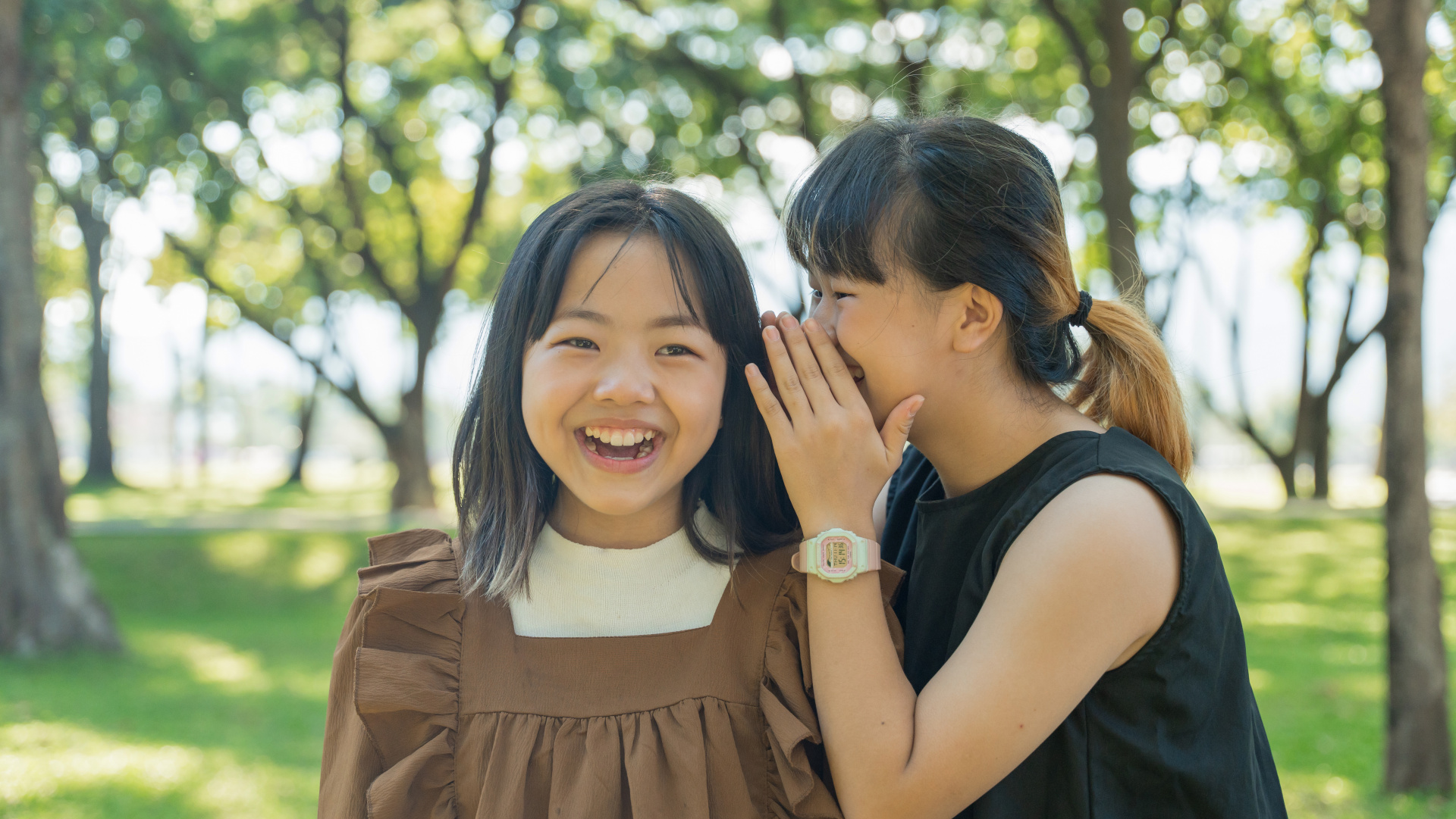 A girl whispering something in the ear of another girl. 