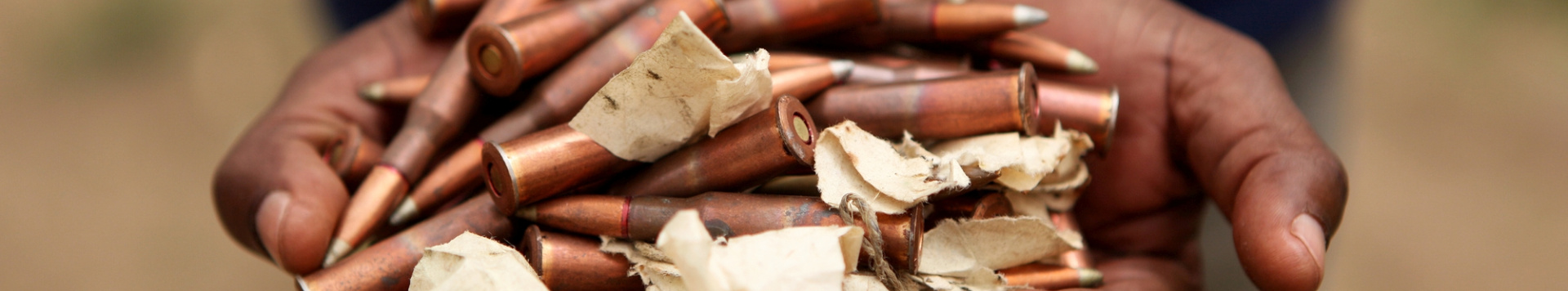 Close-up of somebody holding a pile of bullets and torn papers in his hand.