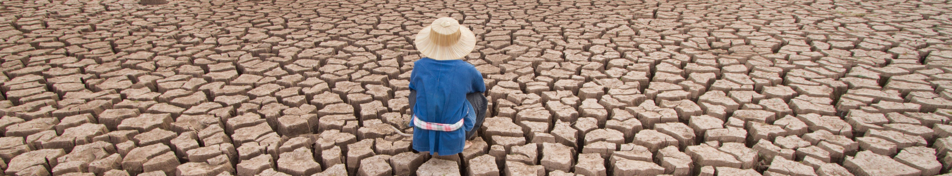 A man sitting on an extremely dry piece of land. 