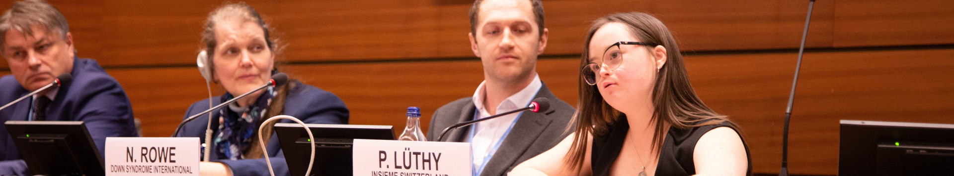 A young woman with Down syndrome speaking from the podium at a UN event.