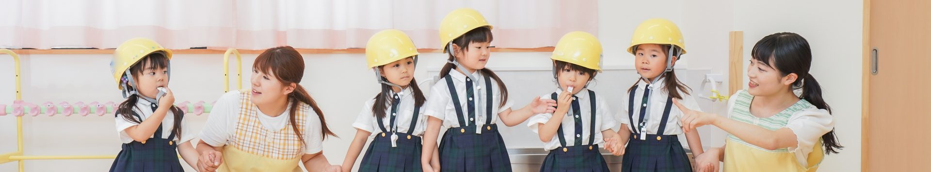 Two educators and five girls are lined up. The girls wear helmets and the educators guide them the way.